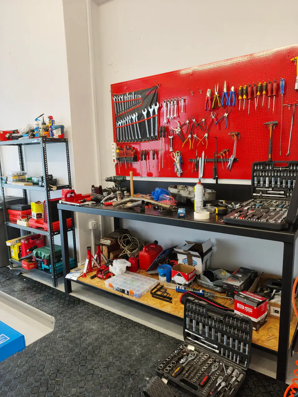 The workbench under the red tool wall. Socket sets on top, shelving beside it.