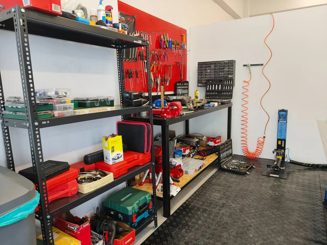 Steel shelving full of tool cases beside the workbench and the air line.