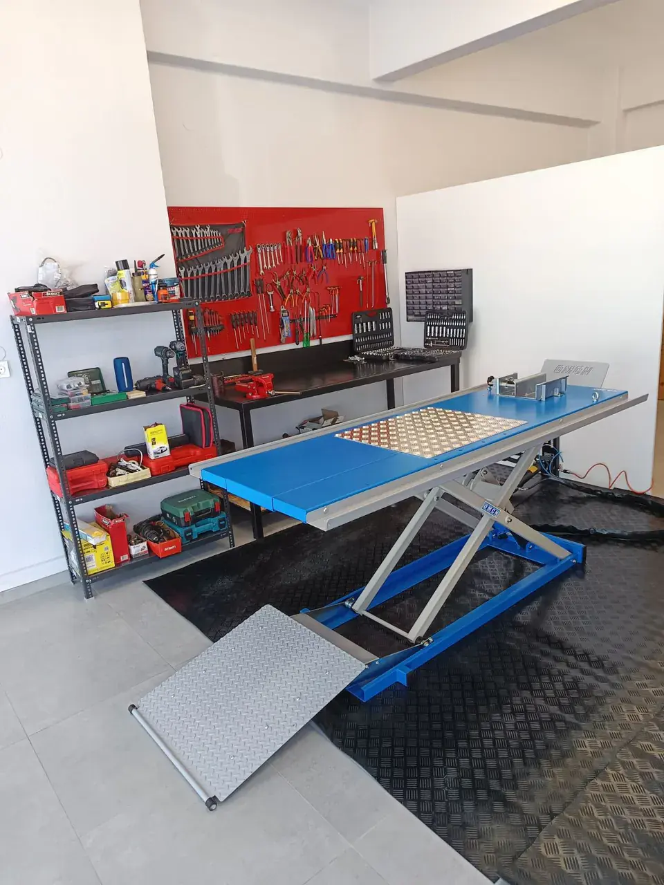 The blue OMCN scissor lift in front of the workbench and the red tool wall.