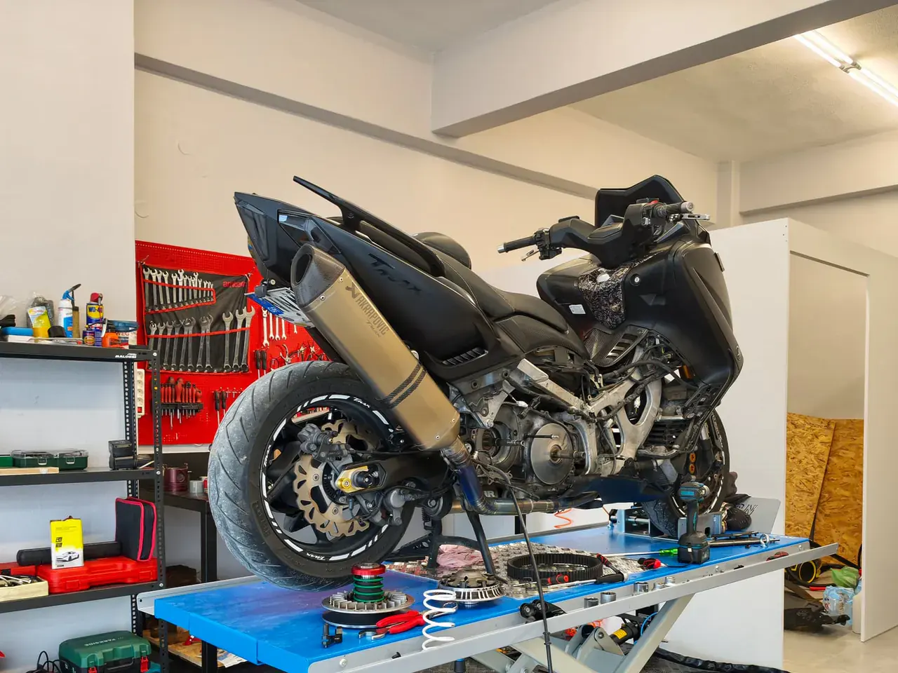Scooter στο ψαλιδωτό ανυψωτικό με ανοιχτό κινητήρα.